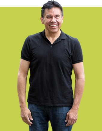 a man wearing a black shirt and jeans smiles for the camera